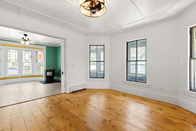 10 Prospect St, Somersworth, NH 03878 - spare room with a wood stove, baseboard heating, healthy amount of natural light, light wood-style floors, and crown molding