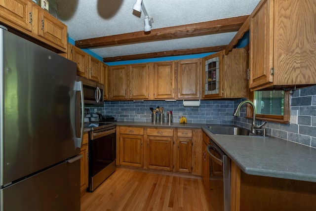 4B Pine Isle Dr Unit B, Derry, NH 03038 - kitchen with appliances with stainless steel finishes, brown cabinetry, light wood-style flooring, decorative backsplash, and beam ceiling