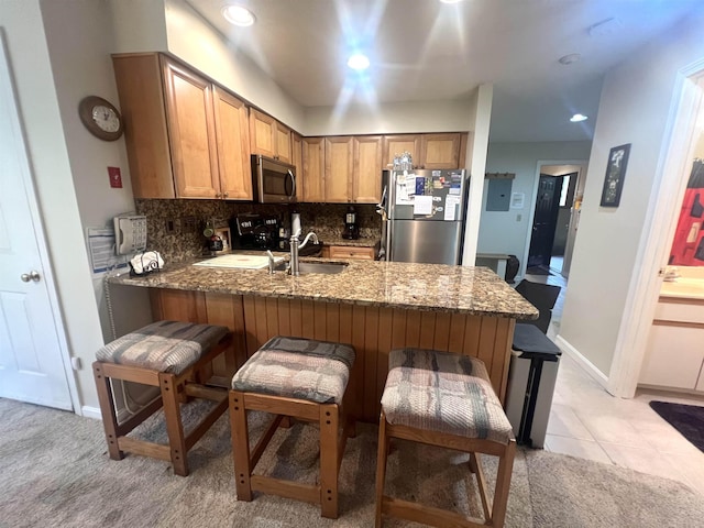 8B Deer Crk, Dover, VT 05356 - kitchen featuring stainless steel appliances, a peninsula, decorative backsplash, dark stone counters, and a breakfast bar area