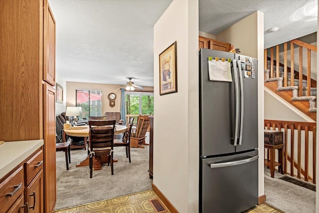 79 Dunvegan Woods Dr Unit 79, Hampton, NH 03842 - kitchen featuring freestanding refrigerator, light colored carpet, brown cabinetry, a ceiling fan, and a textured ceiling