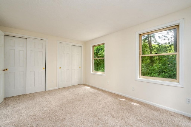 129 Fisherville Rd Unit 26, Concord, NH 03303 - unfurnished bedroom featuring two closets, multiple windows, and carpet floors