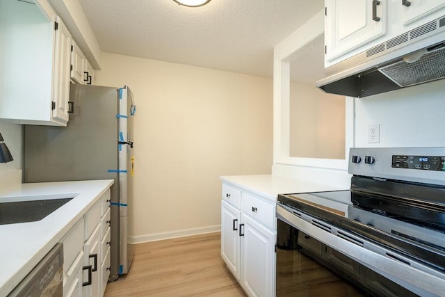 129 Fisherville Rd Unit 26, Concord, NH 03303 - kitchen featuring appliances with stainless steel finishes, exhaust hood, light wood-style flooring, and white cabinetry