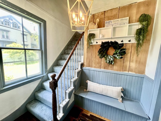 21 Main St, Rockingham, VT 05154 - stairway with a chandelier, plenty of natural light, a wainscoted wall, and wooden walls