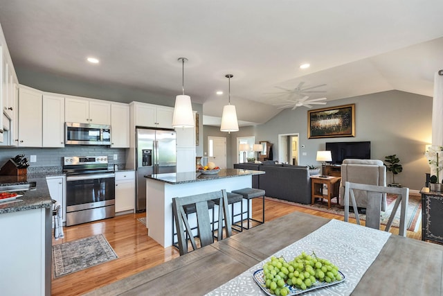 25 Reserve Way Unit 60, Milford, NH 03055 - kitchen featuring stainless steel appliances, a kitchen island, vaulted ceiling, a breakfast bar area, and a ceiling fan