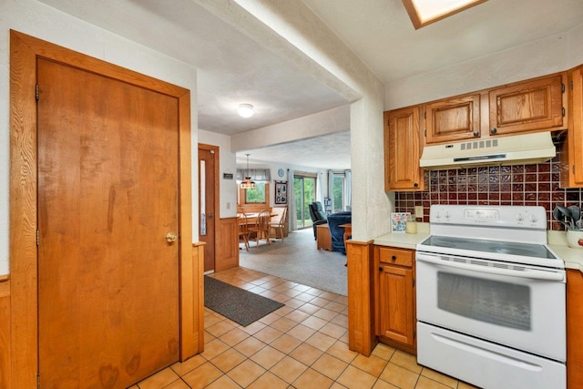 F22 Christmas Mountain Rd Unit 22, Bartlett, NH 03812 - kitchen with under cabinet range hood, white electric range oven, light countertops, light tile patterned floors, and brown cabinets
