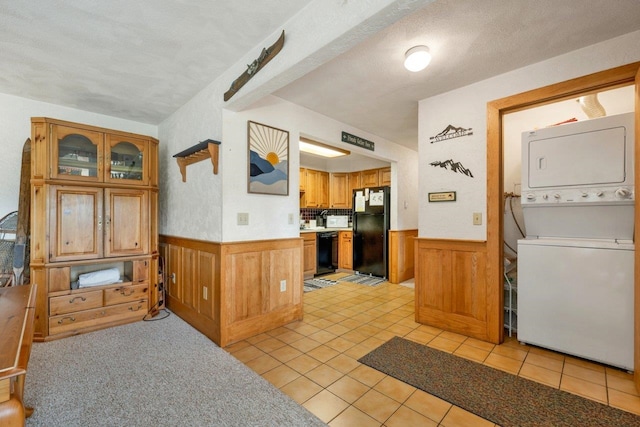 F22 Christmas Mountain Rd Unit 22, Bartlett, NH 03812 - kitchen with black appliances, stacked washer / drying machine, a wainscoted wall, light countertops, and brown cabinetry