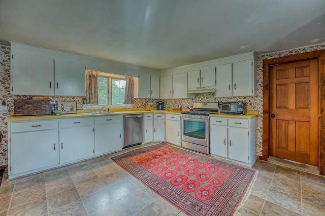 3247 Rte 302, Lisbon, NH 03585 - kitchen featuring stainless steel appliances, under cabinet range hood, light countertops, stone finish flooring, and white cabinets