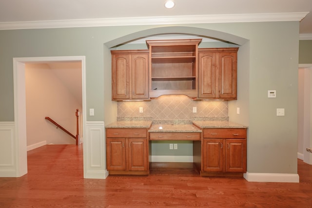2C Manor Dr, Hooksett, NH 03106 - kitchen with light stone countertops, crown molding, light wood finished floors, backsplash, and brown cabinetry
