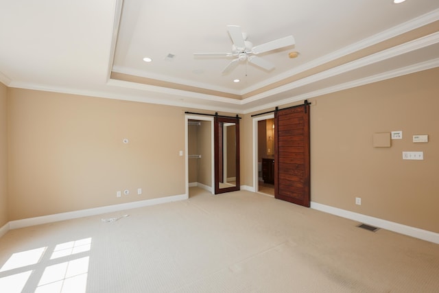 2C Manor Dr, Hooksett, NH 03106 - unfurnished bedroom featuring a barn door, a tray ceiling, light carpet, crown molding, and recessed lighting