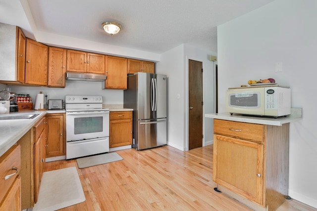 22 Pelham Rd, Hudson, NH 03051 - kitchen with white appliances, under cabinet range hood, light wood-type flooring, and brown cabinets