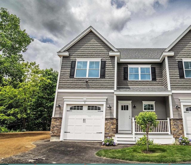 50 Newfields Rd Unit A, Exeter, NH 03833 - view of front of property featuring stone siding, a garage, covered porch, asphalt driveway, and a shingled roof