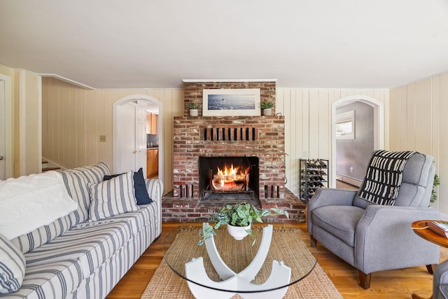 626 County Rd, New London, NH 03257 - living area with arched walkways, a fireplace, wood finished floors, baseboard heating, and wooden walls