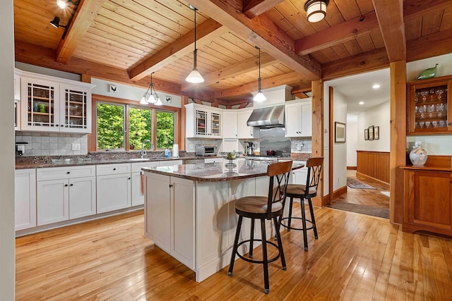 82 Little Cove Rd, New London, NH 03257 - kitchen with wall chimney exhaust hood, light wood-type flooring, a wooden ceiling with exposed beams, a kitchen island, and a kitchen breakfast bar