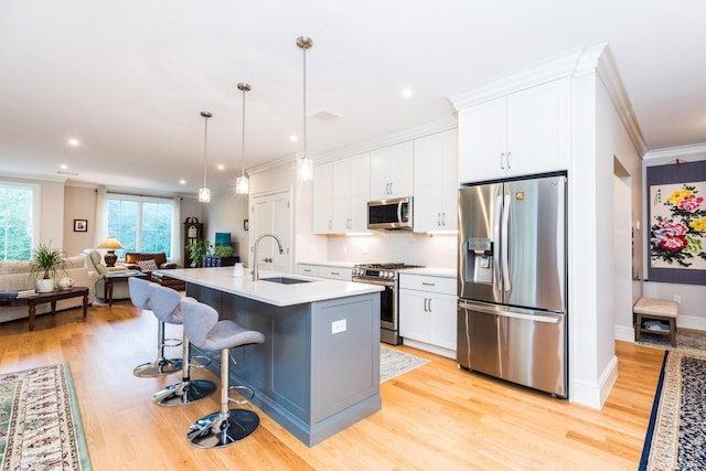32 Willey Creek Rd Unit 402, Exeter, NH 03833 - kitchen featuring stainless steel appliances, ornamental molding, light wood-style flooring, open floor plan, and white cabinets