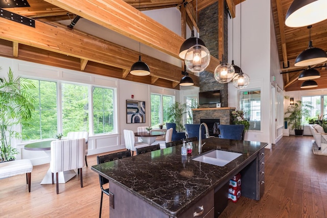 32 Willey Creek Rd Unit 402, Exeter, NH 03833 - kitchen with open floor plan, a fireplace, wood finished floors, beam ceiling, and dark stone counters