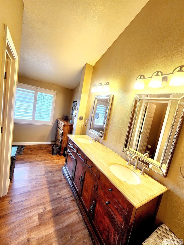 3348 Current Ct, Reno, NV 89509 - bathroom featuring lofted ceiling, wood finished floors, double vanity, baseboards, and a textured wall