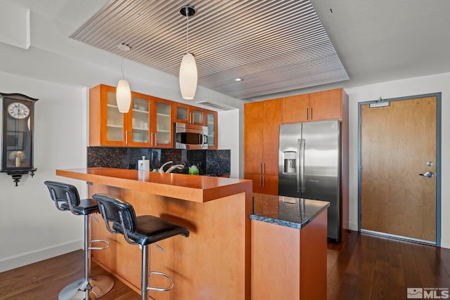 255 N Sierra St Unit 2013, Reno, NV 89501 - kitchen with stainless steel appliances, glass insert cabinets, brown cabinets, dark wood-style floors, and decorative backsplash