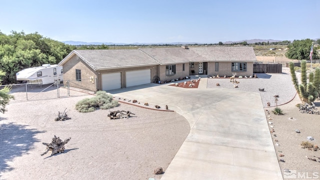 4223 Rancheria Rd, Fallon, NV 89406 - ranch-style house featuring fence, an attached garage, concrete driveway, a tiled roof, and a mountain view