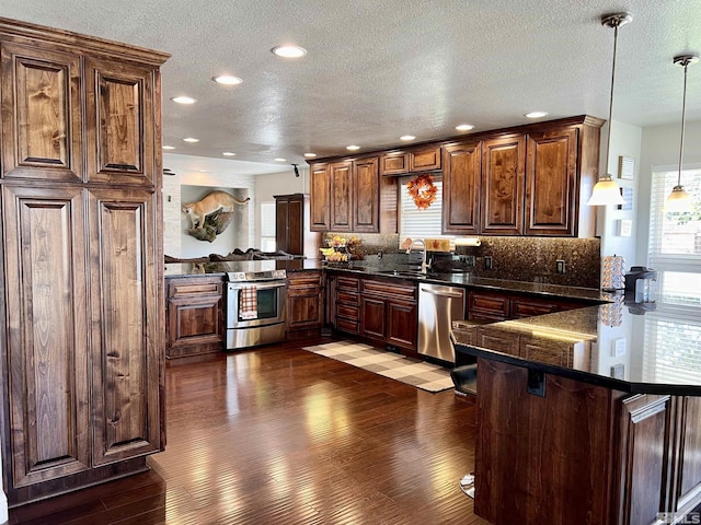 310 N Mountain View St, Yerington, NV 89447 - kitchen featuring stainless steel appliances, a peninsula, hardwood / wood-style flooring, backsplash, and a textured ceiling