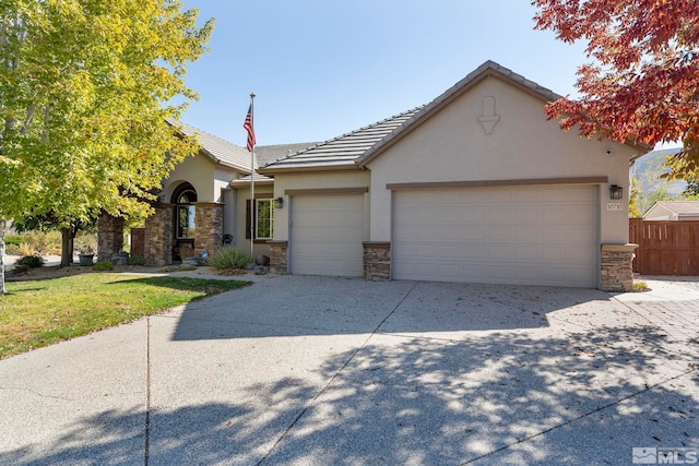 10710 Ivy Gate, Reno, NV 89521 - view of front of home with stone siding, stucco siding, an attached garage, driveway, and fence