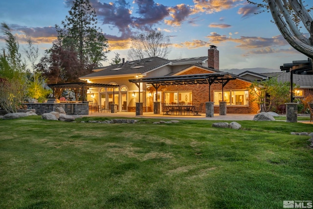 1865 Olive Ln, Reno, NV 89511 - back of property at dusk featuring a chimney, a patio area, and a yard
