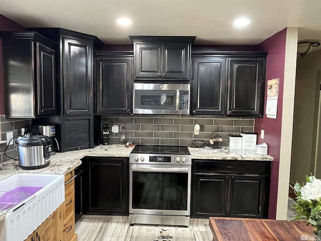 3205 Saint Clair Rd, Fallon, NV 89406 - kitchen featuring appliances with stainless steel finishes, dark cabinets, tasteful backsplash, and light stone countertops
