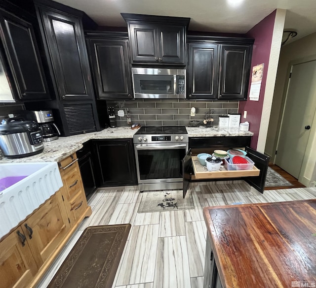 3205 Saint Clair Rd, Fallon, NV 89406 - kitchen featuring stainless steel appliances, dark cabinetry, backsplash, and light stone countertops