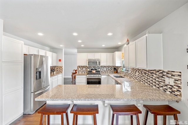 17850 Brushland Dr, Reno, NV 89508 - kitchen with stainless steel appliances, a peninsula, a sink, tasteful backsplash, and white cabinets