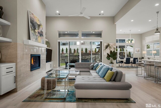 718 W Pleasant Oak Trl, Reno, NV 89511 - living room with light wood-style floors, recessed lighting, a tiled fireplace, ceiling fan, and a towering ceiling