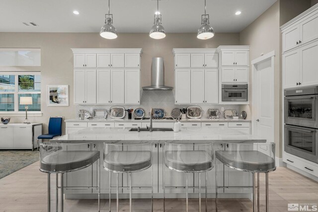 718 W Pleasant Oak Trl, Reno, NV 89511 - kitchen featuring wall chimney range hood, stainless steel double oven, white cabinets, decorative light fixtures, and a breakfast bar area