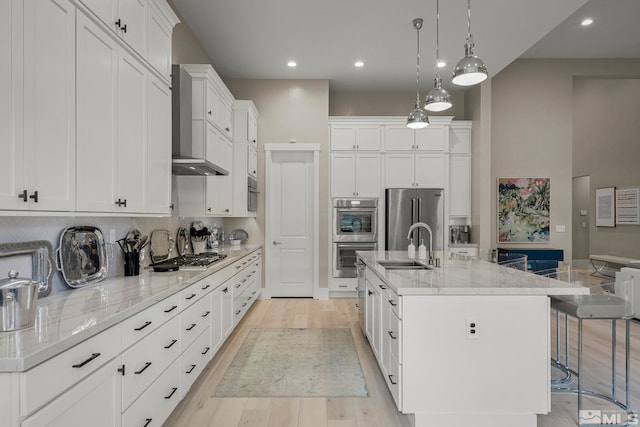 718 W Pleasant Oak Trl, Reno, NV 89511 - kitchen with stainless steel appliances, a breakfast bar area, an island with sink, white cabinets, and light wood finished floors
