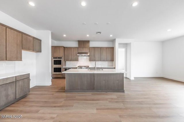 7511 Hoback Dr Unit Windsong 54, Sparks, NV 89436 - kitchen with double oven, under cabinet range hood, light countertops, tasteful backsplash, and light wood-type flooring