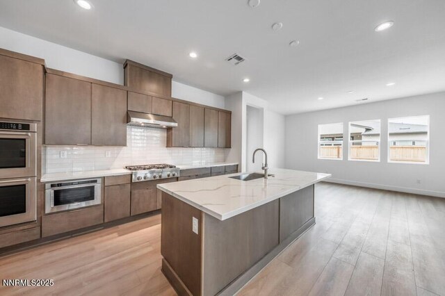 7511 Hoback Dr Unit Windsong 54, Sparks, NV 89436 - kitchen featuring stainless steel appliances, light wood-style floors, tasteful backsplash, under cabinet range hood, and recessed lighting
