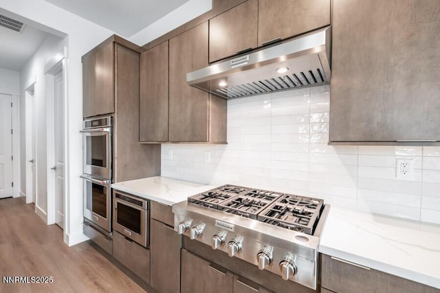 7511 Hoback Dr Unit Windsong 54, Sparks, NV 89436 - kitchen featuring exhaust hood, appliances with stainless steel finishes, tasteful backsplash, and light wood-style flooring