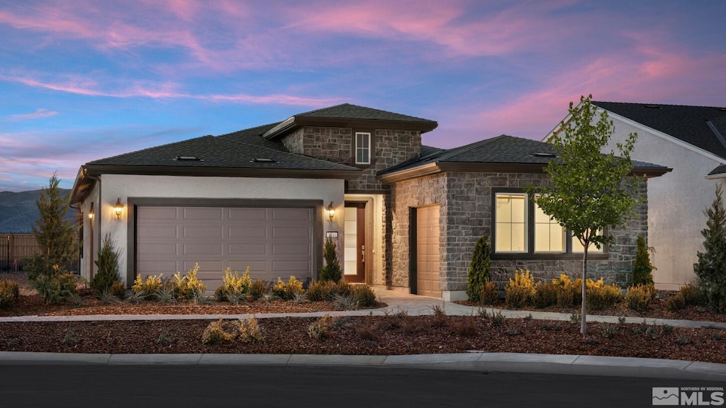view of front facade with stone siding, an attached garage, stucco siding, and a shingled roof