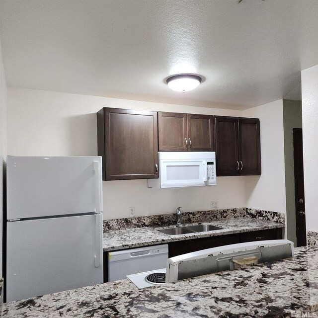2450 Lymbery St Unit 137, Reno, NV 89509 - kitchen featuring white appliances, a sink, dark brown cabinets, and light stone counters
