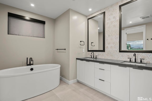 62 Caballada St, Reno, NV 89511 - full bath with a freestanding tub, double vanity, recessed lighting, backsplash, and baseboards