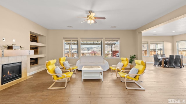 11725 Paradise View Dr, Sparks, NV 89441 - living area featuring built in features, ceiling fan, wood finished floors, a tiled fireplace, and baseboards