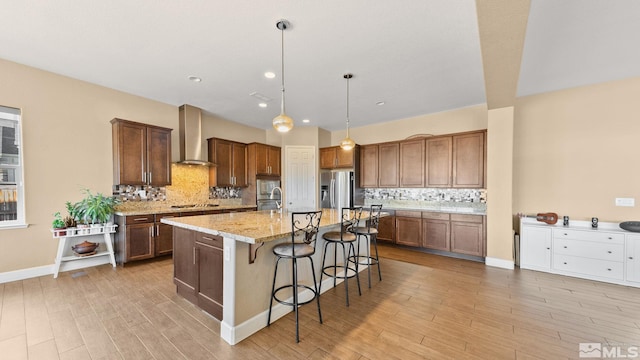 11725 Paradise View Dr, Sparks, NV 89441 - kitchen with wall chimney exhaust hood, appliances with stainless steel finishes, light wood-style flooring, a kitchen breakfast bar, and tasteful backsplash