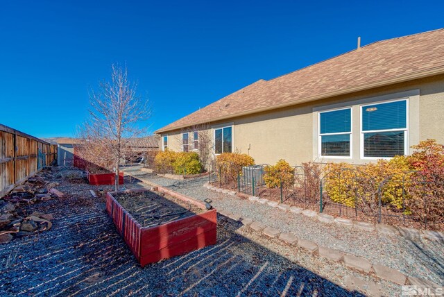 11725 Paradise View Dr, Sparks, NV 89441 - view of home's exterior with stucco siding, a vegetable garden, a fenced backyard, and roof with shingles
