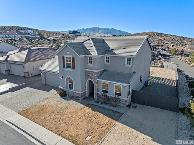 8389 Opal Ranch Way, Reno, NV 89506 - view of front of house with stucco siding, stone siding, a mountain view, a garage, and driveway