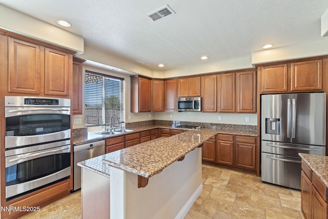 8389 Opal Ranch Way, Reno, NV 89506 - kitchen featuring appliances with stainless steel finishes, a sink, brown cabinets, recessed lighting, and a textured ceiling