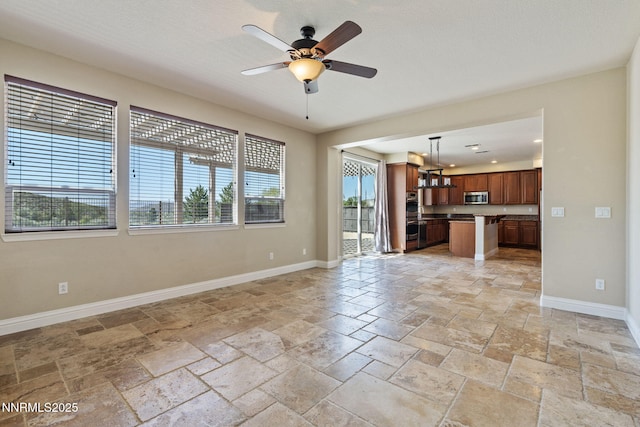 8389 Opal Ranch Way, Reno, NV 89506 - unfurnished living room featuring stone tile floors, a ceiling fan, and baseboards