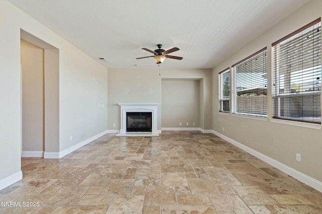 8389 Opal Ranch Way, Reno, NV 89506 - unfurnished living room with stone tile floors, a ceiling fan, baseboards, and a glass covered fireplace
