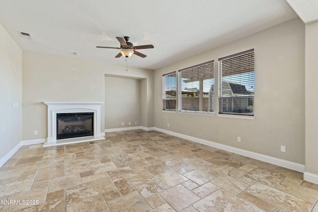 8389 Opal Ranch Way, Reno, NV 89506 - unfurnished living room with stone tile floors, ceiling fan, a glass covered fireplace, and baseboards