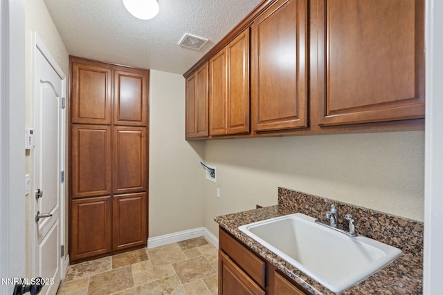 8389 Opal Ranch Way, Reno, NV 89506 - laundry room featuring hookup for a washing machine, cabinet space, baseboards, a textured ceiling, and light stone finish flooring