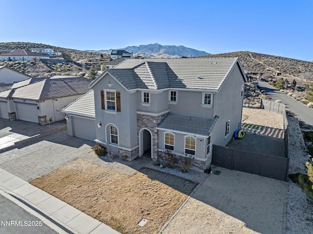 8389 Opal Ranch Way, Reno, NV 89506 - view of front of house with stucco siding, stone siding, a garage, a mountain view, and driveway