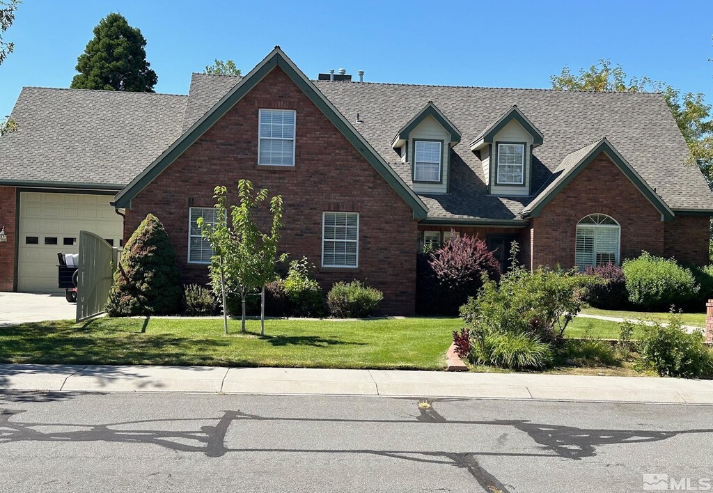 972 Springfield, Gardnerville, NV 89460 - view of front of home with an attached garage, brick siding, roof with shingles, and a front lawn
