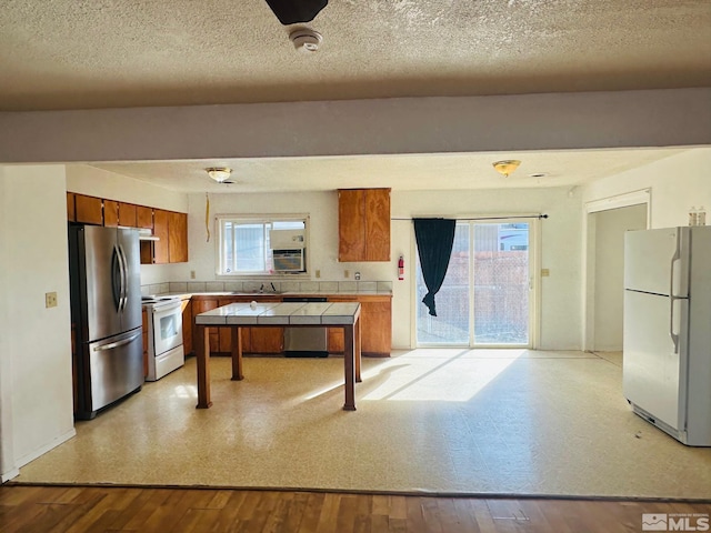 815 16th St, Lovelock, NV 89419 - kitchen featuring white appliances, brown cabinets, tile countertops, a sink, and a textured ceiling