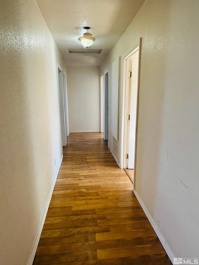 815 16th St, Lovelock, NV 89419 - corridor with wood finished floors, a textured wall, and baseboards